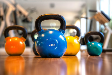 Colorful kettlebells in a row on floor in a gym, select focus