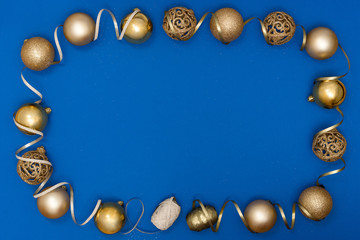 New Year and Christmas composition. Golden shiny balls, decorative ribbon on blue paper background