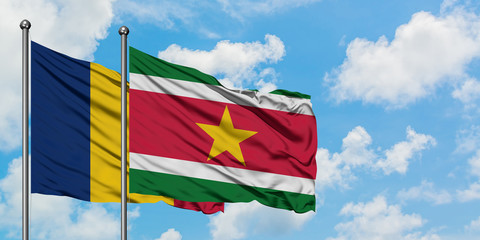 Chad and Suriname flag waving in the wind against white cloudy blue sky together. Diplomacy concept, international relations.