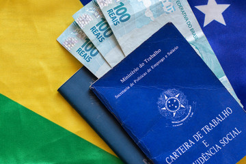 Brazilian document work and social security with one hundred reais banknotes over the Brazilian flag