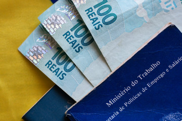 Obraz premium Brazilian document work and social security with one hundred reais banknotes over the Brazilian flag