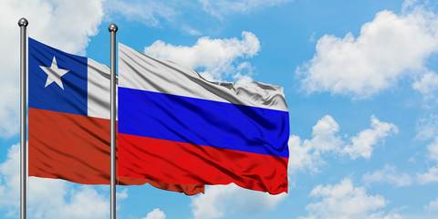 Chile and Russia flag waving in the wind against white cloudy blue sky together. Diplomacy concept, international relations.