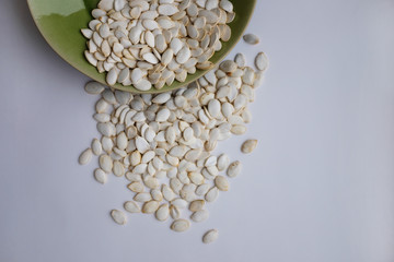 Vintage ceramic green plate with scattered pumpkin seeds on the white background. Top view, flat lay