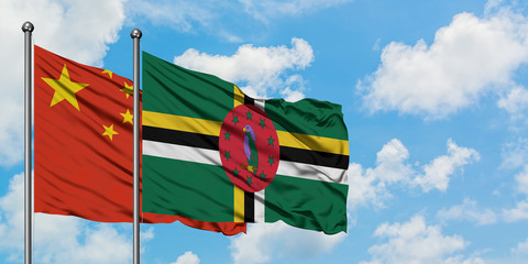 China and Dominica flag waving in the wind against white cloudy blue sky together. Diplomacy concept, international relations.