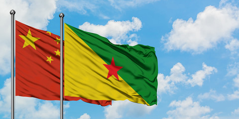 China and French Guiana flag waving in the wind against white cloudy blue sky together. Diplomacy concept, international relations.