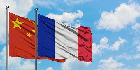 China and France flag waving in the wind against white cloudy blue sky together. Diplomacy concept,...