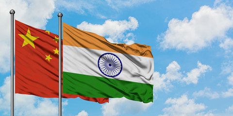China and India flag waving in the wind against white cloudy blue sky together. Diplomacy concept, international relations.