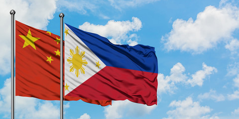 China and Philippines flag waving in the wind against white cloudy blue sky together. Diplomacy concept, international relations.
