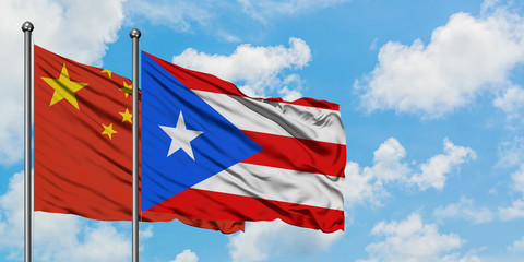 China and Puerto Rico flag waving in the wind against white cloudy blue sky together. Diplomacy concept, international relations.