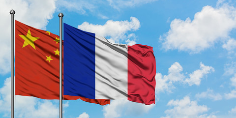 China and Reunion flag waving in the wind against white cloudy blue sky together. Diplomacy concept, international relations.