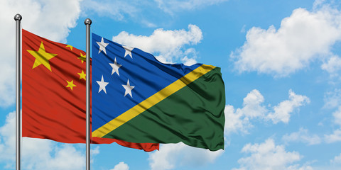 China and Solomon Islands flag waving in the wind against white cloudy blue sky together. Diplomacy concept, international relations.