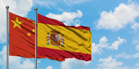China and Spain flag waving in the wind against white cloudy blue sky together. Diplomacy concept, international relations.