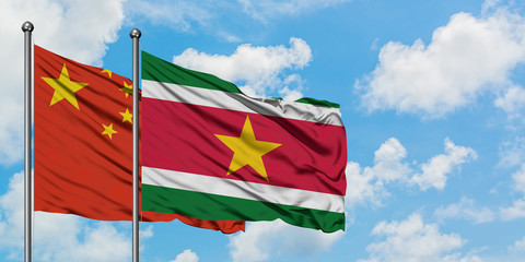 China and Suriname flag waving in the wind against white cloudy blue sky together. Diplomacy concept, international relations.