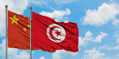 China and Tunisia flag waving in the wind against white cloudy blue sky together. Diplomacy concept, international relations.