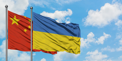 China and Ukraine flag waving in the wind against white cloudy blue sky together. Diplomacy concept, international relations.