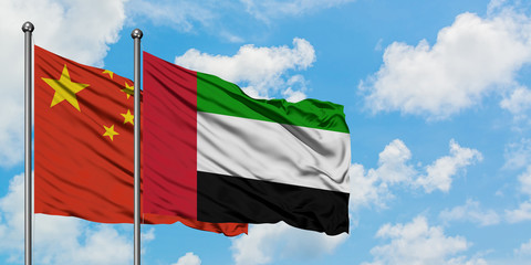 China and United Arab Emirates flag waving in the wind against white cloudy blue sky together. Diplomacy concept, international relations.