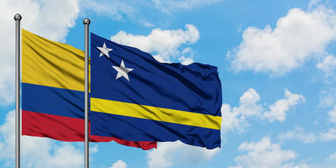 Colombia and Curacao flag waving in the wind against white cloudy blue sky together. Diplomacy concept, international relations.