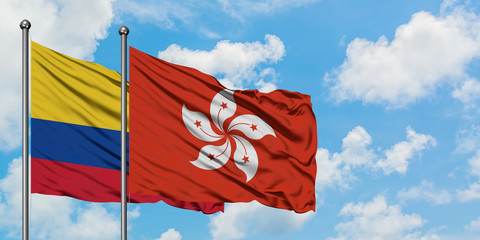 Colombia and Hong Kong flag waving in the wind against white cloudy blue sky together. Diplomacy...