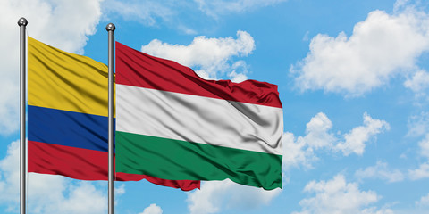 Colombia and Hungary flag waving in the wind against white cloudy blue sky together. Diplomacy concept, international relations.