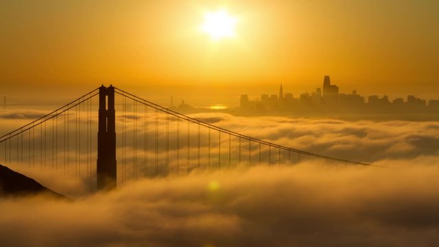 Golden Gate Bridge sunrise with low fog and city view