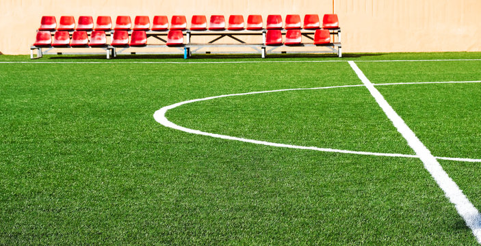 Artificial grass turf and rows of red specatator seats.