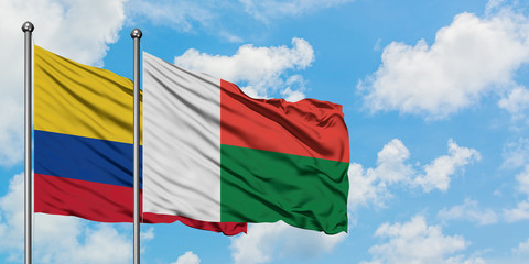 Colombia and Madagascar flag waving in the wind against white cloudy blue sky together. Diplomacy concept, international relations.
