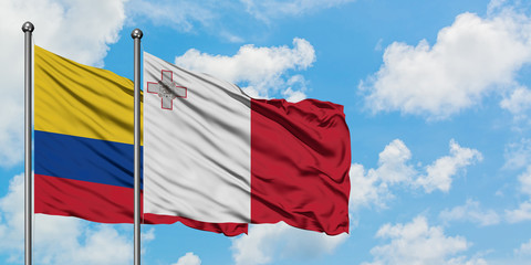 Colombia and Malta flag waving in the wind against white cloudy blue sky together. Diplomacy concept, international relations.
