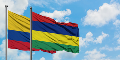 Colombia and Mauritius flag waving in the wind against white cloudy blue sky together. Diplomacy concept, international relations.