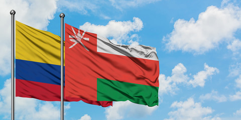 Colombia and Oman flag waving in the wind against white cloudy blue sky together. Diplomacy concept, international relations.