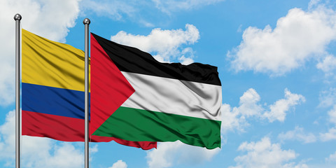 Colombia and Palestine flag waving in the wind against white cloudy blue sky together. Diplomacy concept, international relations.