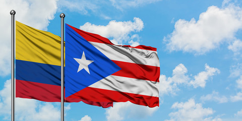 Colombia and Puerto Rico flag waving in the wind against white cloudy blue sky together. Diplomacy concept, international relations.