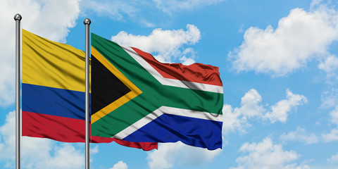 Colombia and South Africa flag waving in the wind against white cloudy blue sky together. Diplomacy concept, international relations.