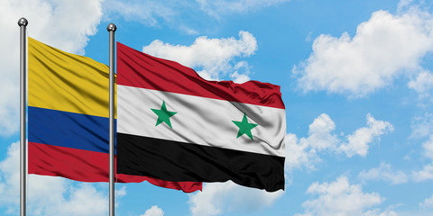 Colombia and Syria flag waving in the wind against white cloudy blue sky together. Diplomacy...