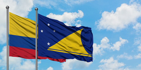 Colombia and Tokelau flag waving in the wind against white cloudy blue sky together. Diplomacy...