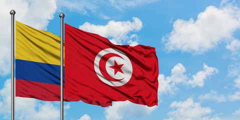 Colombia and Tunisia flag waving in the wind against white cloudy blue sky together. Diplomacy concept, international relations.