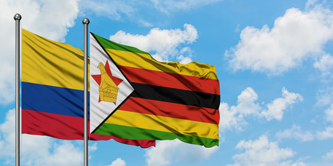 Colombia and Zimbabwe flag waving in the wind against white cloudy blue sky together. Diplomacy concept, international relations.