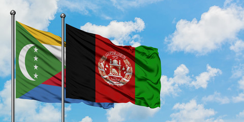 Comoros and Afghanistan flag waving in the wind against white cloudy blue sky together. Diplomacy...