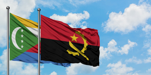 Comoros and Angola flag waving in the wind against white cloudy blue sky together. Diplomacy concept, international relations.
