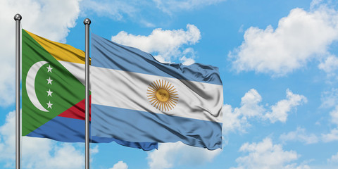 Comoros and Argentina flag waving in the wind against white cloudy blue sky together. Diplomacy...