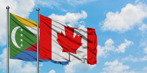 Comoros and Canada flag waving in the wind against white cloudy blue sky together. Diplomacy concept, international relations.