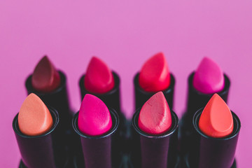eauty industry still-life with group of colorful lipsticks lined up on pink background shot from 45...