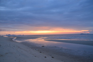 Fototapeta na wymiar A threatening stormy but picturesque tropical orange and grey coloured cloudy coastal sunrise seascape.