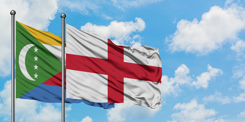 Comoros and England flag waving in the wind against white cloudy blue sky together. Diplomacy concept, international relations.