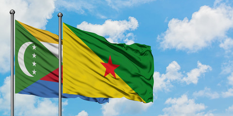 Comoros and French Guiana flag waving in the wind against white cloudy blue sky together. Diplomacy concept, international relations.