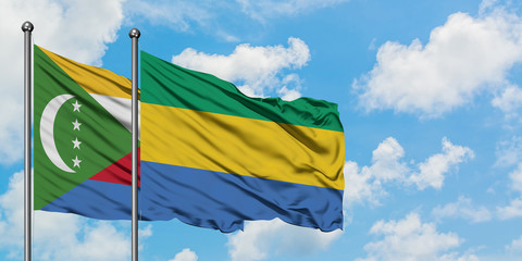 Comoros and Gabon flag waving in the wind against white cloudy blue sky together. Diplomacy...