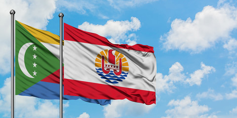 Comoros and French Polynesia flag waving in the wind against white cloudy blue sky together....