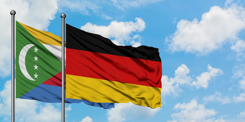 Comoros and Germany flag waving in the wind against white cloudy blue sky together. Diplomacy concept, international relations.
