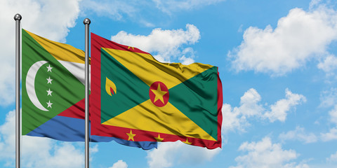 Comoros and Grenada flag waving in the wind against white cloudy blue sky together. Diplomacy concept, international relations.