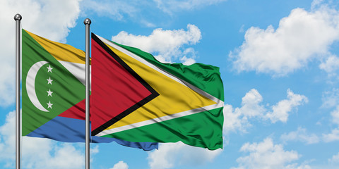 Comoros and Guyana flag waving in the wind against white cloudy blue sky together. Diplomacy concept, international relations.