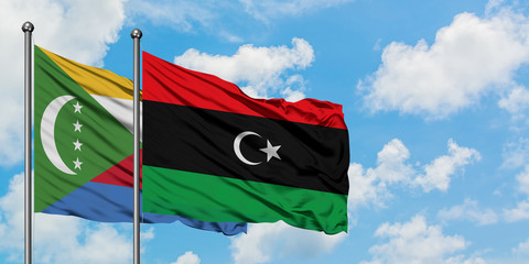 Comoros and Libya flag waving in the wind against white cloudy blue sky together. Diplomacy...